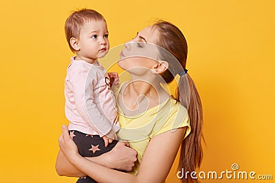 A young caring mother tries to calm down her crying daughter. A tear is going to run down cute baby`s cheek. A disappointed child Stock Photo