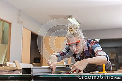 young carpenter woman wear uniform and goggles working use measuring tape size wood. craftsman profession in wood factory. wood Stock Photo