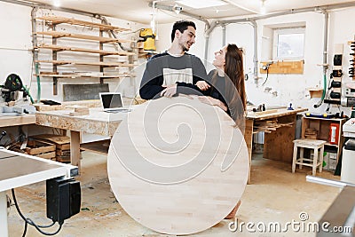 Young carpenter in carpenter workshop. The man holds a wooden round board for the text. Copyspace. young specialist, startup Stock Photo
