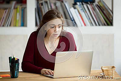 Young casual businesswoman staring at laptop screen with surpris Stock Photo