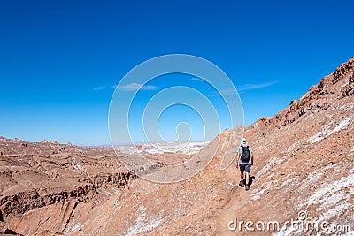Young casual man with backpack on the path at moon like landscape of Valle de la Luna Moon valley, Chile Stock Photo