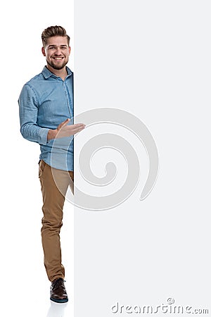 Young casual man smiling and presenting a blank billboard Stock Photo