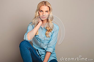 Young casual woman sitting and holds hand on neck Stock Photo