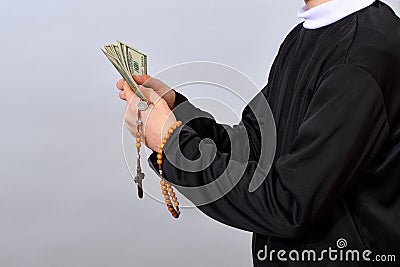 A young Catholic pastor counts dollars after the service. Corruption in Christianity and Catholicism Stock Photo