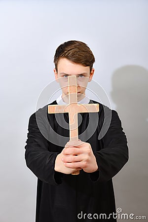 A young Catholic priest holds a cross in front of him. The concept of driving out the devil and evil spirits Stock Photo