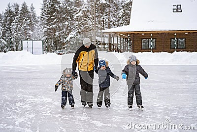 Young caucasian bearded man teach boys how to skate. Father`s day concept. cute caucasian boys learning to skate. Stock Photo