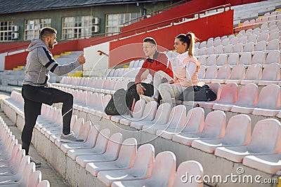 Young caucasian beardy guy standing and talking to smiling couple. personal trainer concept Stock Photo