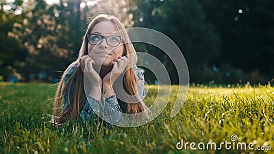 Young caucasian brunette daydreaming while laying on the grass in the park. Relaxation in nature Stock Photo