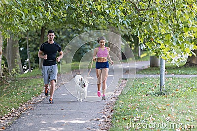 Young caucasian couple with dog running in park, couple jogging together Stock Photo