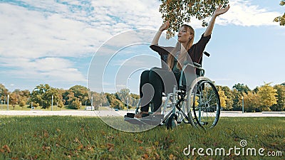 Young caucasian disabled woman listening music and hand dancing under the tree. wide angle Stock Photo