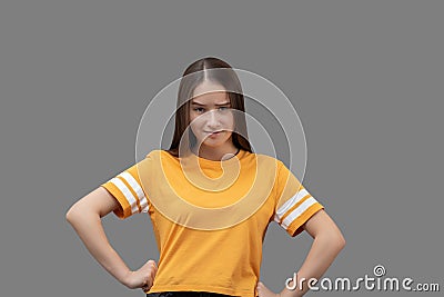 Young caucasian girl with long brown hair smiles, has fun, happy, holds hands on a belt, isolated on gray background Stock Photo