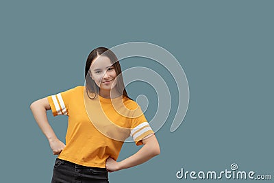 Young caucasian girl with long brown hair smiles, has fun, happy, holds hands on a belt, isolated on gray background Stock Photo