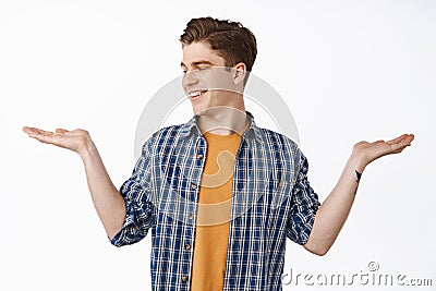 Young caucasian guy showing open hands, holding item and looking at palm with empty place for your produce, smiling Stock Photo