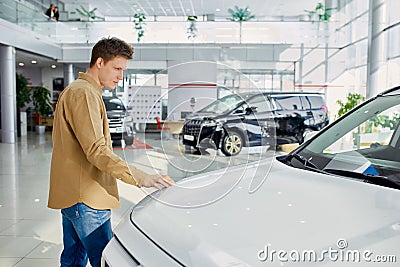 Young caucasian male dream about new car in dealership Stock Photo