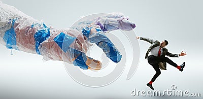 Young caucasian man avoiding big plastic hand on white studio background Stock Photo