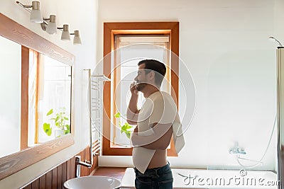 Young Caucasian man brush teeth in modern bathroom Stock Photo