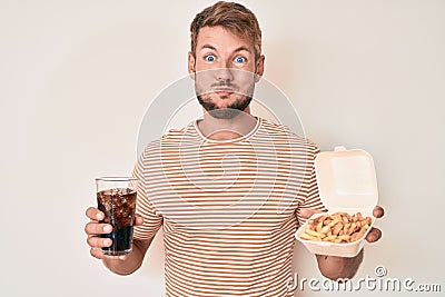 Young caucasian man eating fast food puffing cheeks with funny face Stock Photo