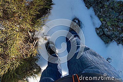 MAN`S LEG WEARING JEANS PANTS AND MOUNTAIN BOOTS FLOORING SNOW Stock Photo