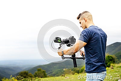 Young caucasian man handling a camera on top of a gimbal while working on recording a scene Stock Photo