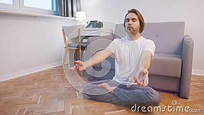 Young caucasian man meditating in his appartment. Mental clarity and wellbeing concept Stock Photo