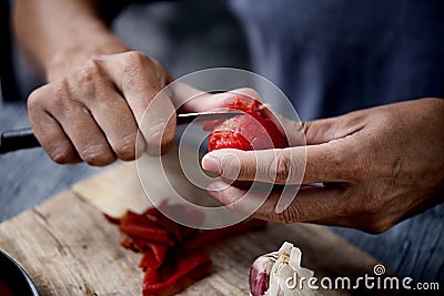 Young caucasian man peels a scalded tomato Stock Photo