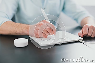 Young caucasian man`s hands writting with stylo on tablet while working on business project in his modern office, taking notes , Stock Photo