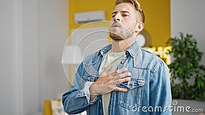 Young caucasian man standing with hand on heart listening to anthem at home Stock Photo