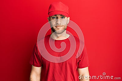 Young caucasian man wearing delivery uniform and cap with serious expression on face Stock Photo