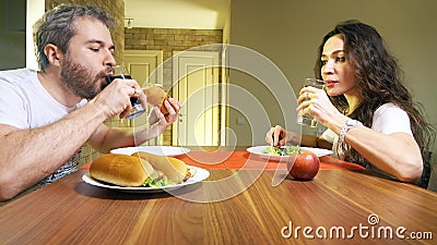 Young caucasian man and woman drinking carbonated soft drink and mineral water. Junk food versus healthy eating concept Stock Photo