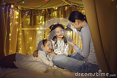 Mother telling magic story to two little daughters with flashlight in hand Stock Photo