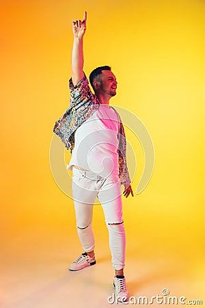 Young caucasian musician, dancer, party host, DJ on gradient background in neon light Stock Photo