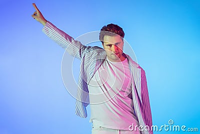 Young caucasian musician, dancer, party host, DJ on gradient background in neon light Stock Photo