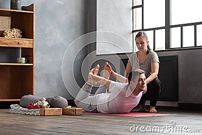 Young caucasian practicing yoga in gym with help of teacher Stock Photo