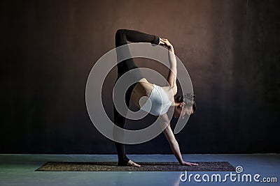 Young caucasian slim yoga girl doing variation of adho mukha shvanasana Stock Photo