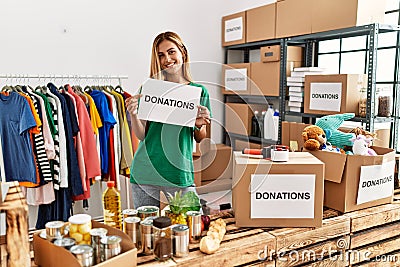 Young caucasian volunteer girl smiling happy holding donations banner at charity center Stock Photo