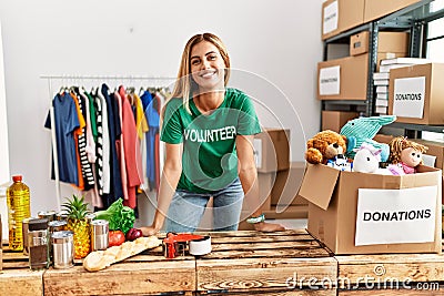 Young caucasian volunteer girl smiling happy standing at charity center Stock Photo
