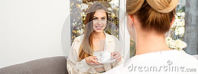 The young caucasian woman with a cup of coffee has an appointment with a female doctor beautician in the hospital office Stock Photo