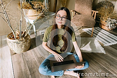 Young caucasian woman dreamed while work on laptop computer , sitting on floor at cozy home in sunny day Stock Photo