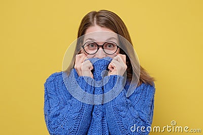 Young caucasian woman in glasses hiding face in blue sweater. Stock Photo