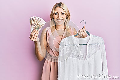 Young caucasian woman holding hanger with t shirt and russian ruble banknotes smiling with a happy and cool smile on face Stock Photo