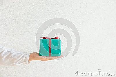 Woman holds in hand gift box wrapped in green paper tied with red ribbon. White background. Christmas New Years Valentine Birthday Stock Photo