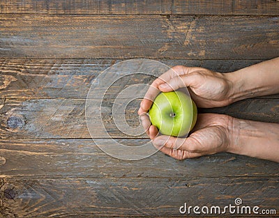 Young caucasian woman holds in hands ripe red apple on dark plank wood background. Thanksgiving autumns harvest gratefulness Stock Photo