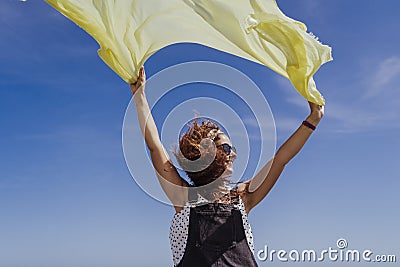 Young caucasian woman outdoors playing with yellow scarf on a windy and sunny day. Lifestyle and summertime Stock Photo