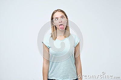 Young caucasian woman shows tongue over gray background. Stock Photo