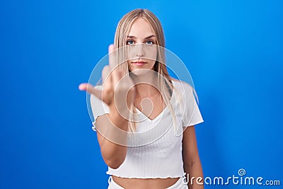 Young caucasian woman standing over blue background showing middle finger, impolite and rude fuck off expression Stock Photo