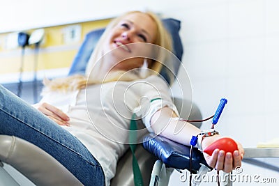 Young caucasian woman with toy heart in the hand donates blood for saving lives and medical research Stock Photo