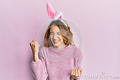 Young caucasian woman wearing cute easter bunny ears celebrating surprised and amazed for success with arms raised and eyes closed Stock Photo