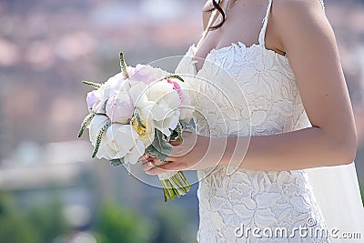 Young Caucasian woman wearing an embroidered wedding dress and holding a round peonies bouquet, an essential accessory for a bride Stock Photo