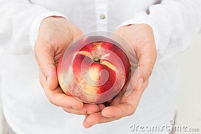 Young Caucasian woman in white shirt holding in hands ripe juicy organic red yellow nectarine. Summer fruits vitamins harvest Stock Photo