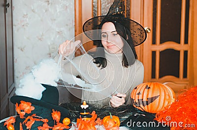 Young caucasian woman in witch hat prepares for halloween and keeps fake spiderweb with smile Stock Photo